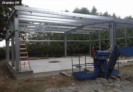 A blue crane is sitting in front of a building under construction