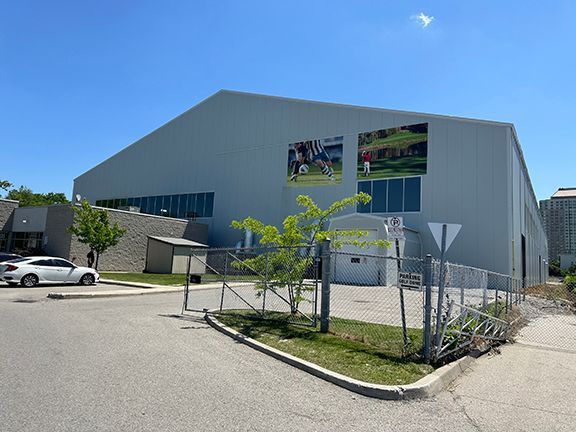 A white car is parked in front of a large building