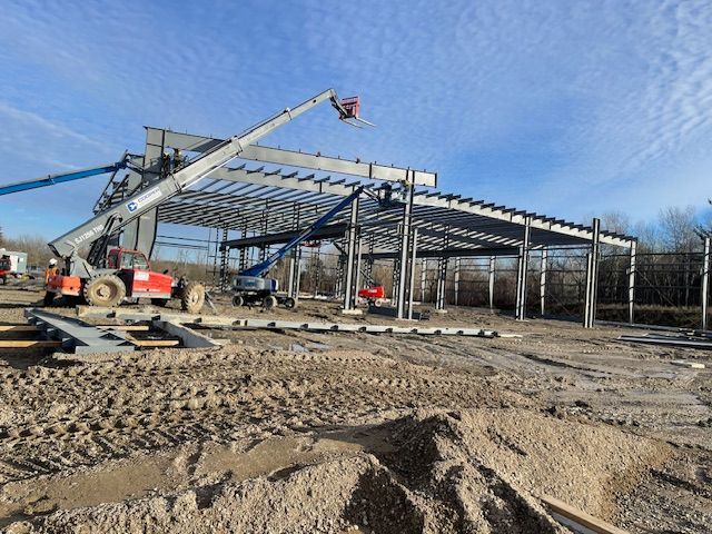 A large metal structure is being built in a dirt field.