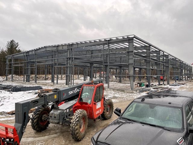 A red forklift is parked in front of a building under construction.