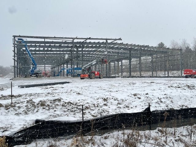 A large metal structure is being built in the snow.