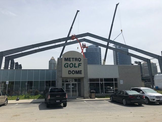 Cars are parked in front of a building that says metro golf dome