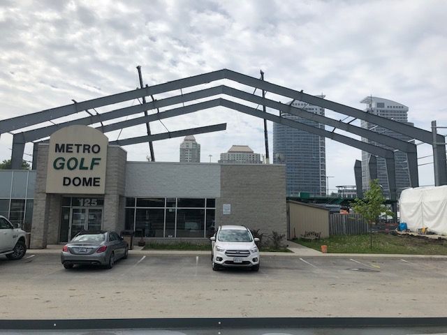 Two cars are parked in front of a building that says metro golf dome.