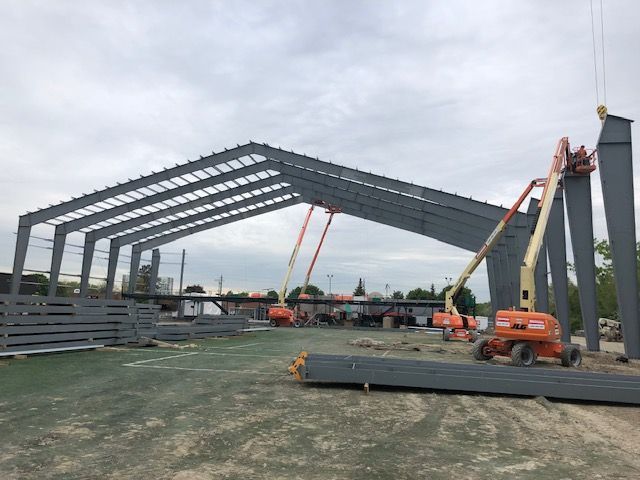 A large metal structure is being built on a dirt field.