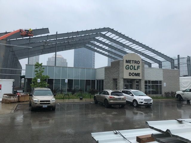 Cars are parked in front of a building that says metro golf dome