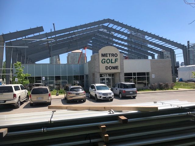 A group of cars are parked in front of a building that says metro golf dome.