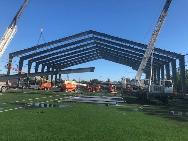 A large metal structure is being built on a soccer field.