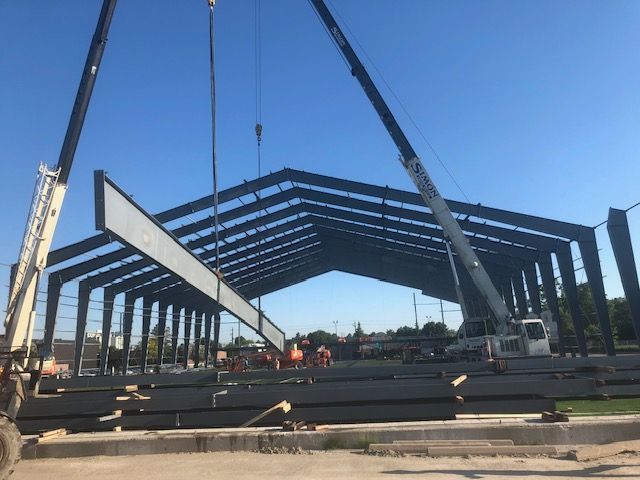 A crane is lifting a beam into a building under construction.