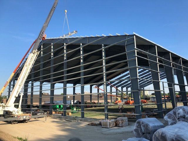 A crane is lifting a roof on a building under construction.