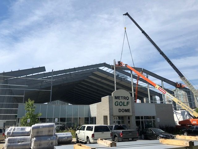 A sign that says metro golf dome is being lifted by a crane