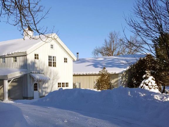 A white house with a snowy driveway in front of it