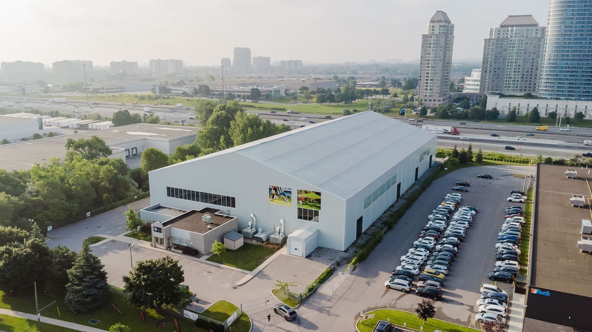 An aerial view of a large white building with a lot of cars parked in front of it.