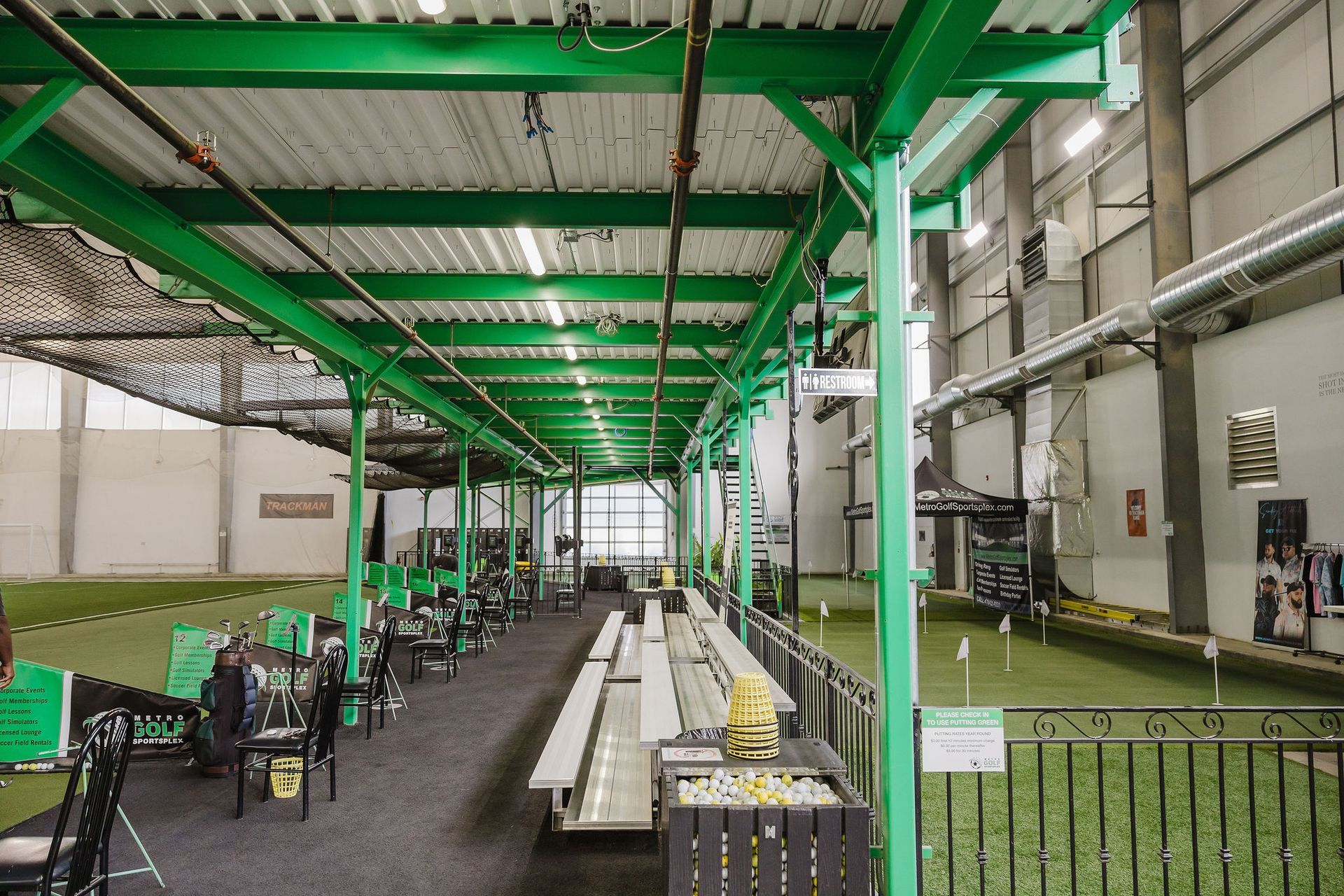 A large indoor gym with green columns and tables and chairs.