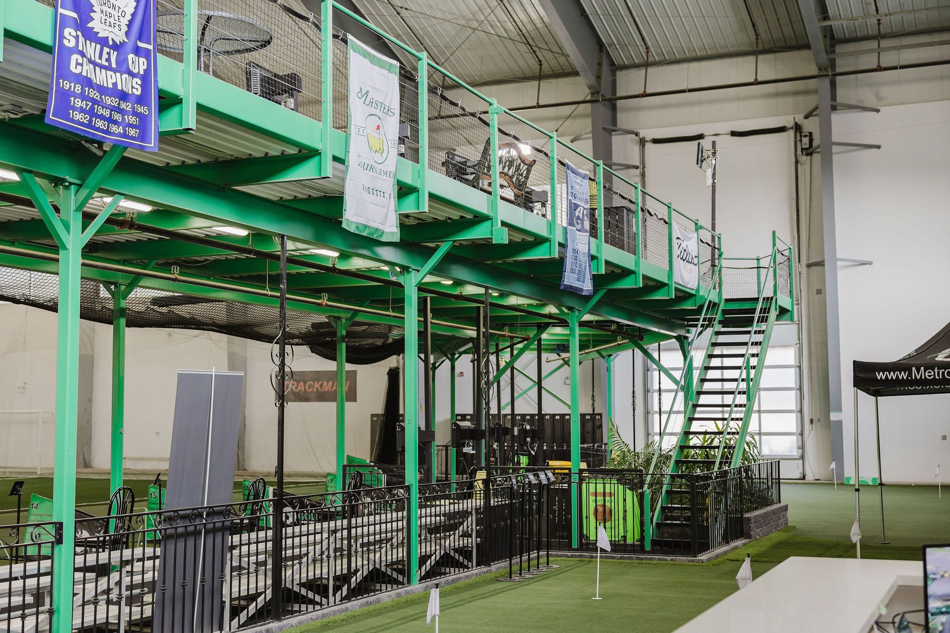 A large indoor gym with a green platform and stairs.