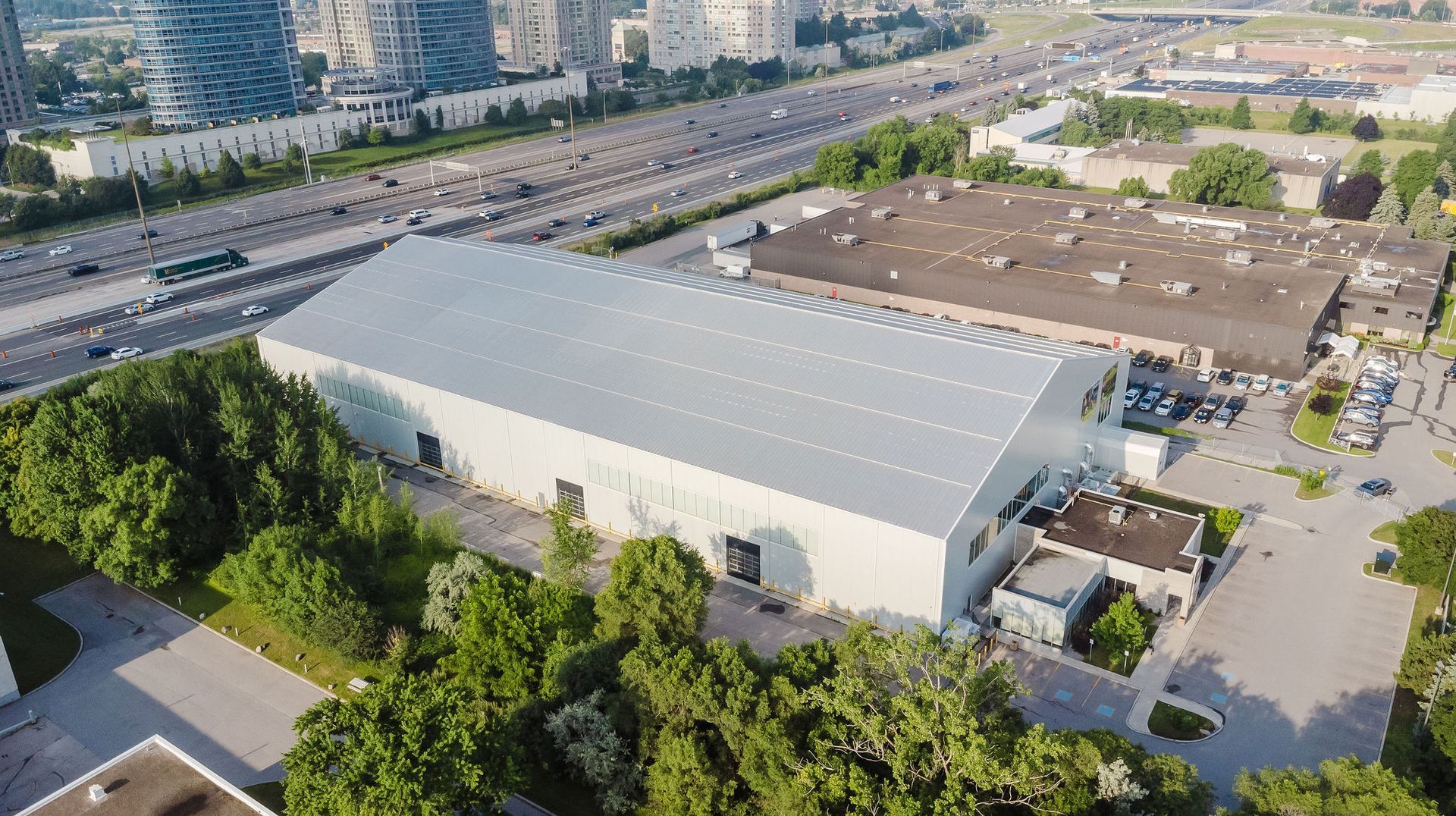 An aerial view of a large white building surrounded by trees and a highway.