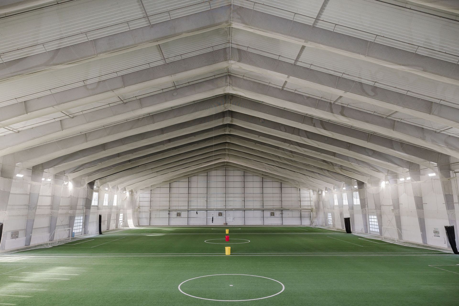 A large indoor soccer field with a yellow cone in the middle of it.