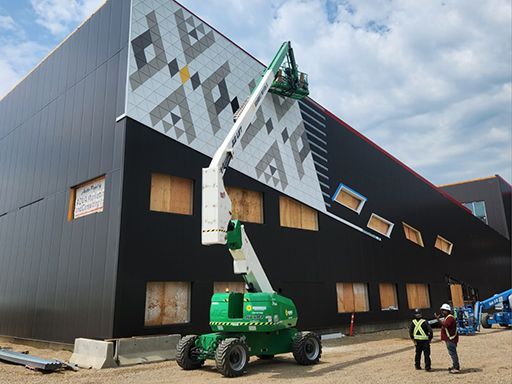 A man is standing in front of a building with a crane on it.