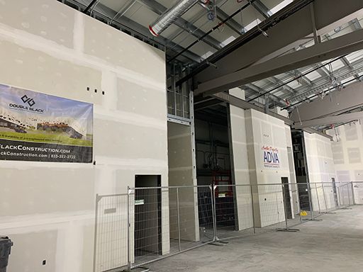 A large empty room with a fence and a sign on the wall.