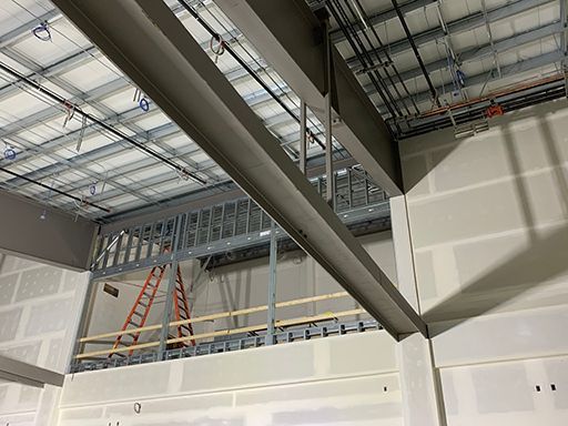 A ladder is hanging from the ceiling of a building under construction.