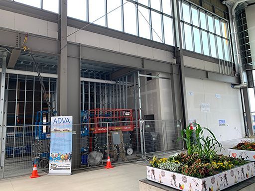 A large building under construction with a planter of flowers in front of it.