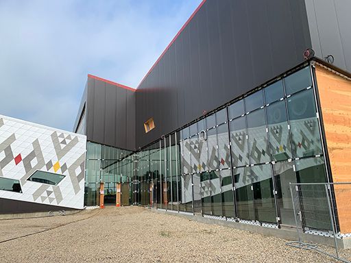 A large building with a lot of windows and a fence in front of it.