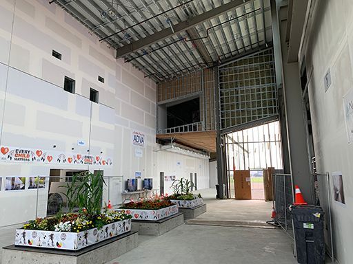 A large empty building with a lot of windows and flowers in pots.