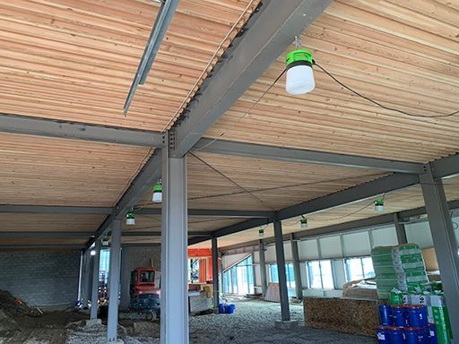 A building under construction with a wooden ceiling and a green light hanging from the ceiling.