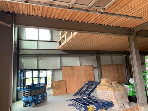 A blue scissor lift is parked inside of a building under construction.