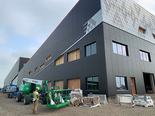 A man is standing in front of a large building under construction.