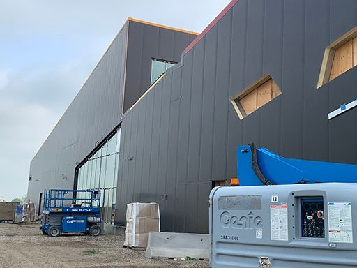 A large building under construction with a blue genie lift in front of it.