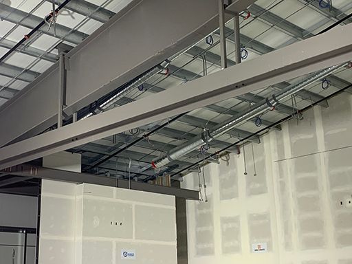 A ceiling with a lot of wires hanging from it in a building under construction.