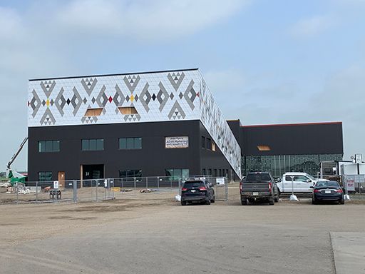 A large building under construction with a lot of cars parked in front of it.