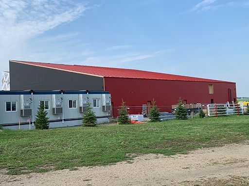 A large red building is sitting in the middle of a grassy field.