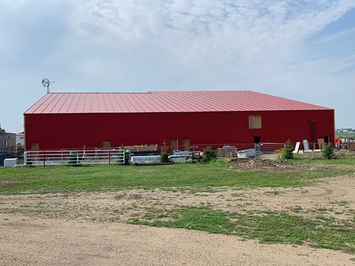 A large red barn is sitting in the middle of a grassy field.