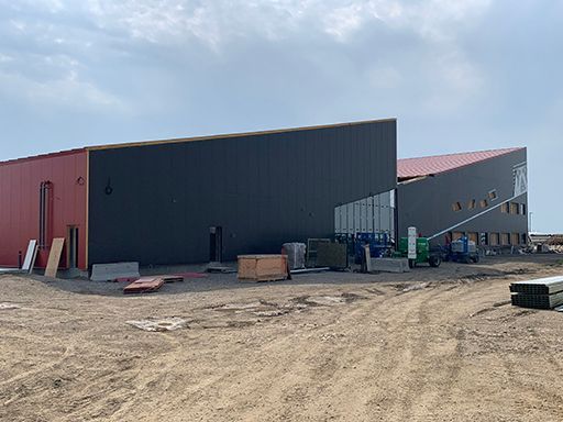 A large building is being built in a dirt field.