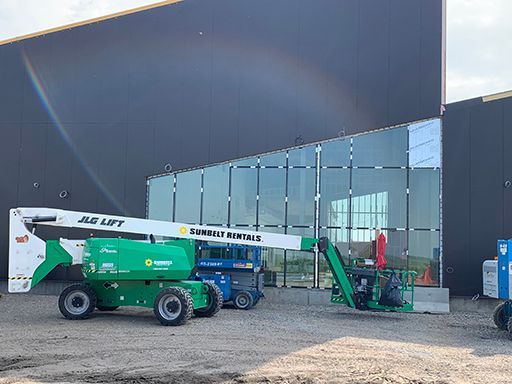 A jlg lift is parked in front of a large building.