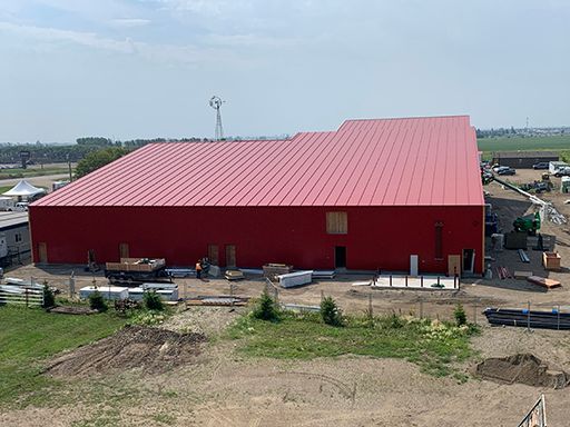 A large red building with a red roof is being built in a field.