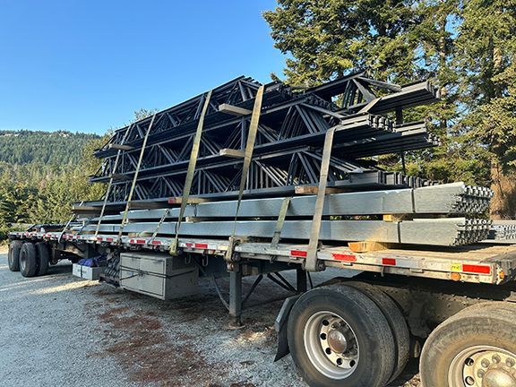 A semi truck is carrying a stack of steel beams to metal building project in Langley, BC.