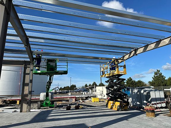 A man on a scissor lift works on a metal structure for Double Black Construction.