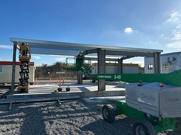 Crane lifts metal roof framing onto storage building at YVR by Double Black Construction.