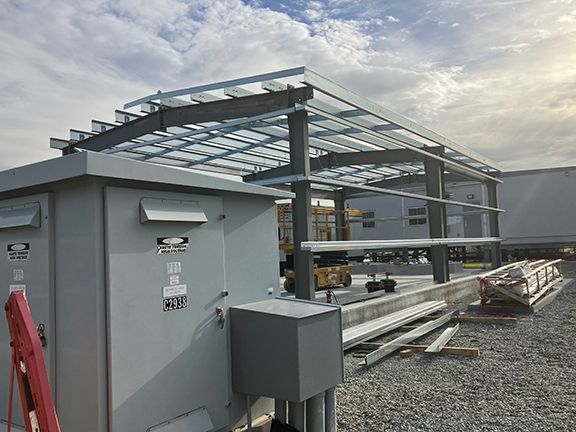 A metal structure is being built in a gravel area.