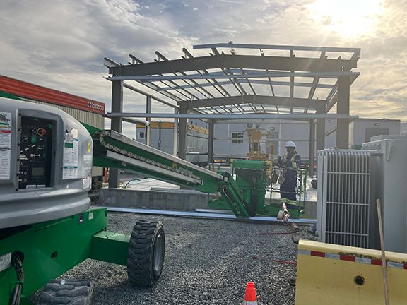 A construction site with a green crane and a man in a hard hat.