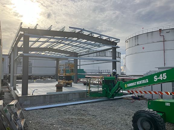 A green crane is sitting in front of a building under construction.