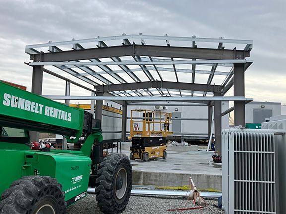 A green sunbelt rental truck is parked in front of a building under construction.