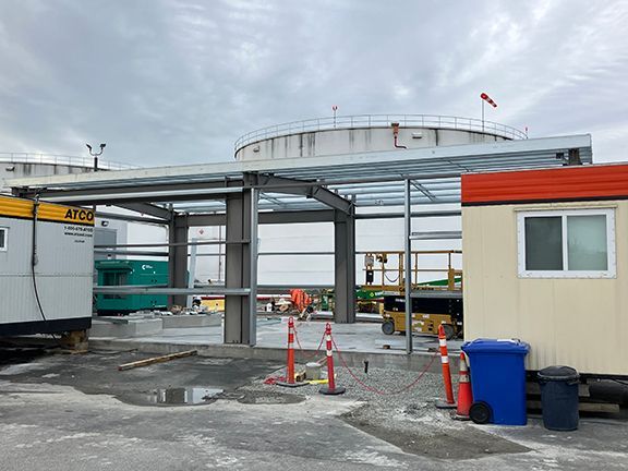 A building under construction with a large tank in the background