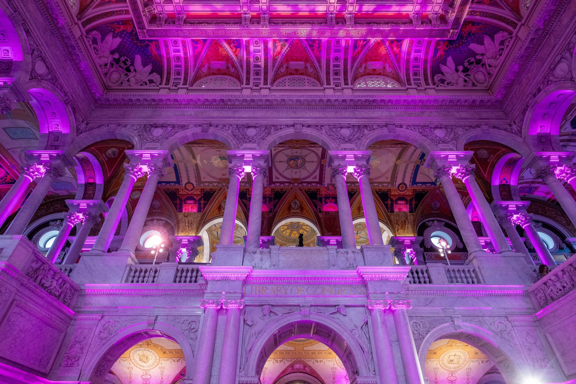 A large building with purple lights on the ceiling and columns.