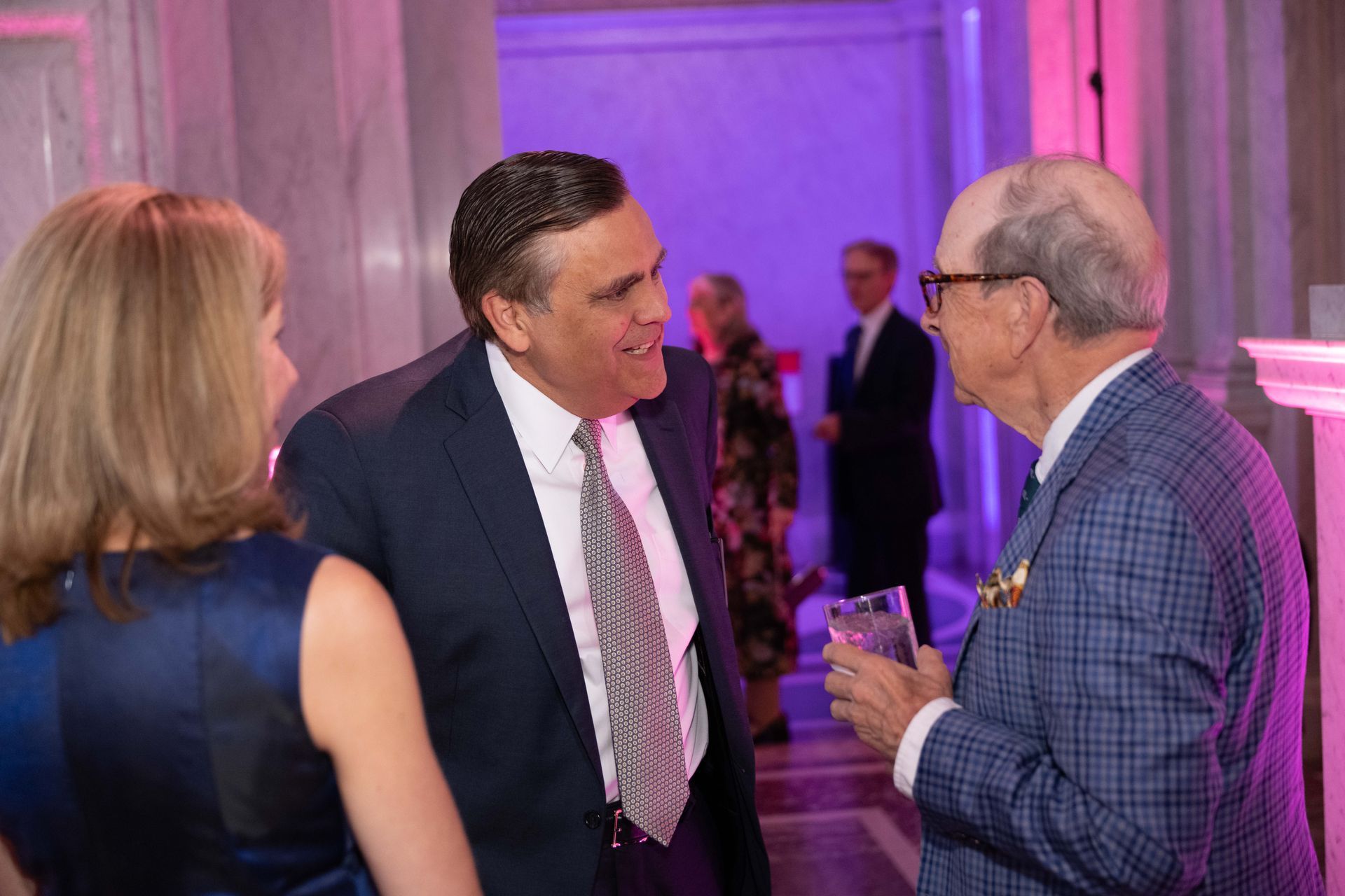 A group of people are standing in a hallway talking to each other.