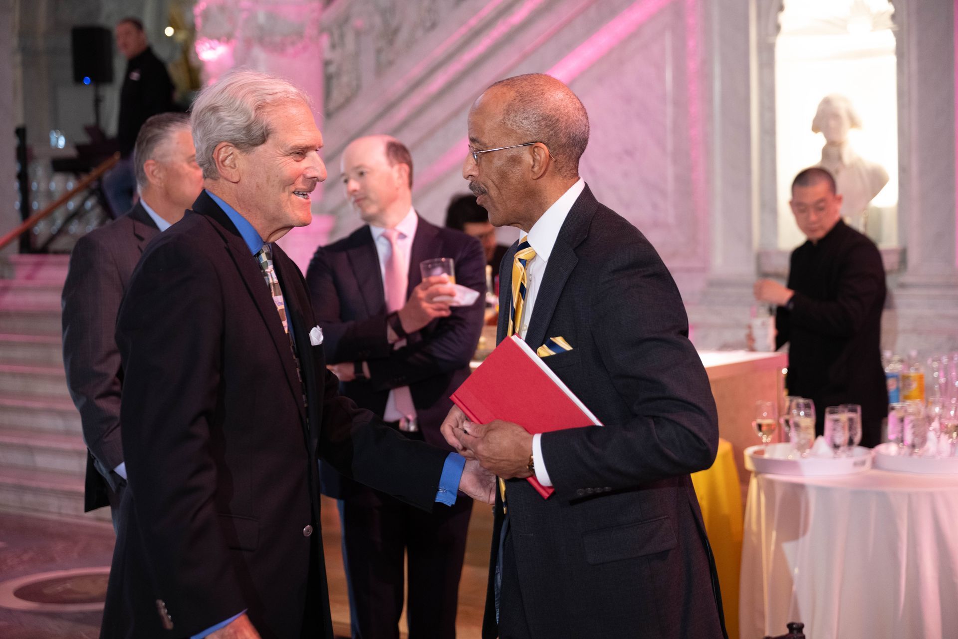 A group of men are standing in a room talking to each other