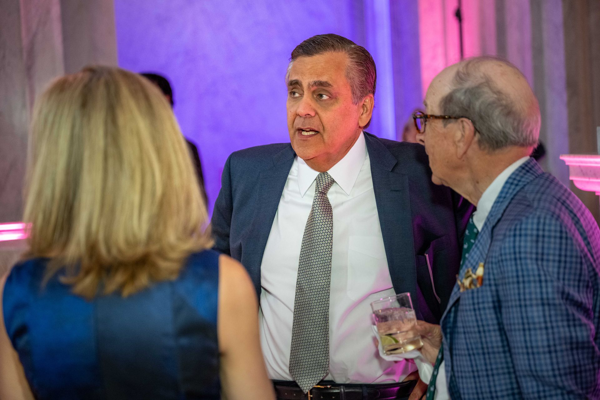 A group of people are standing around talking to each other at a party.