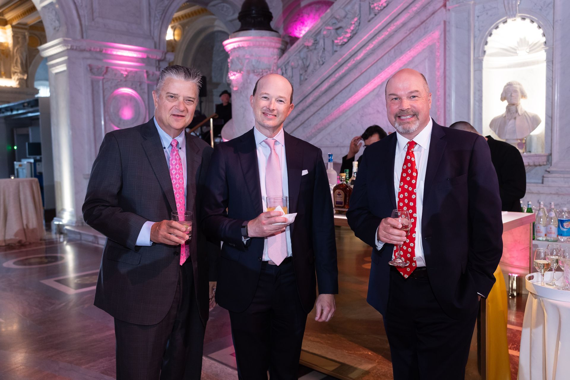 Three men in suits and ties are standing next to each other in a room.